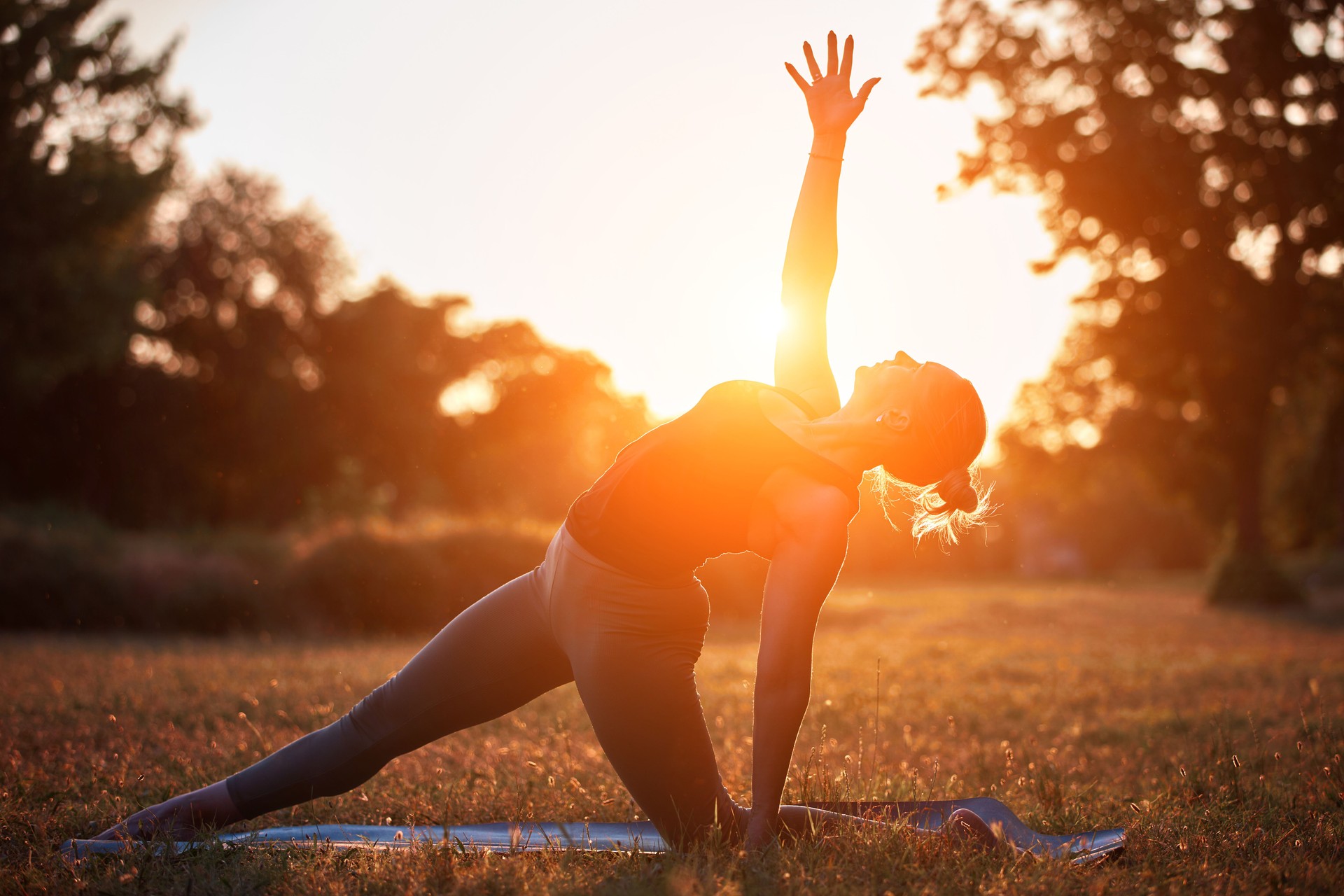 Woman practicing yoga and stretching in the park on a hot sunny summertime day.