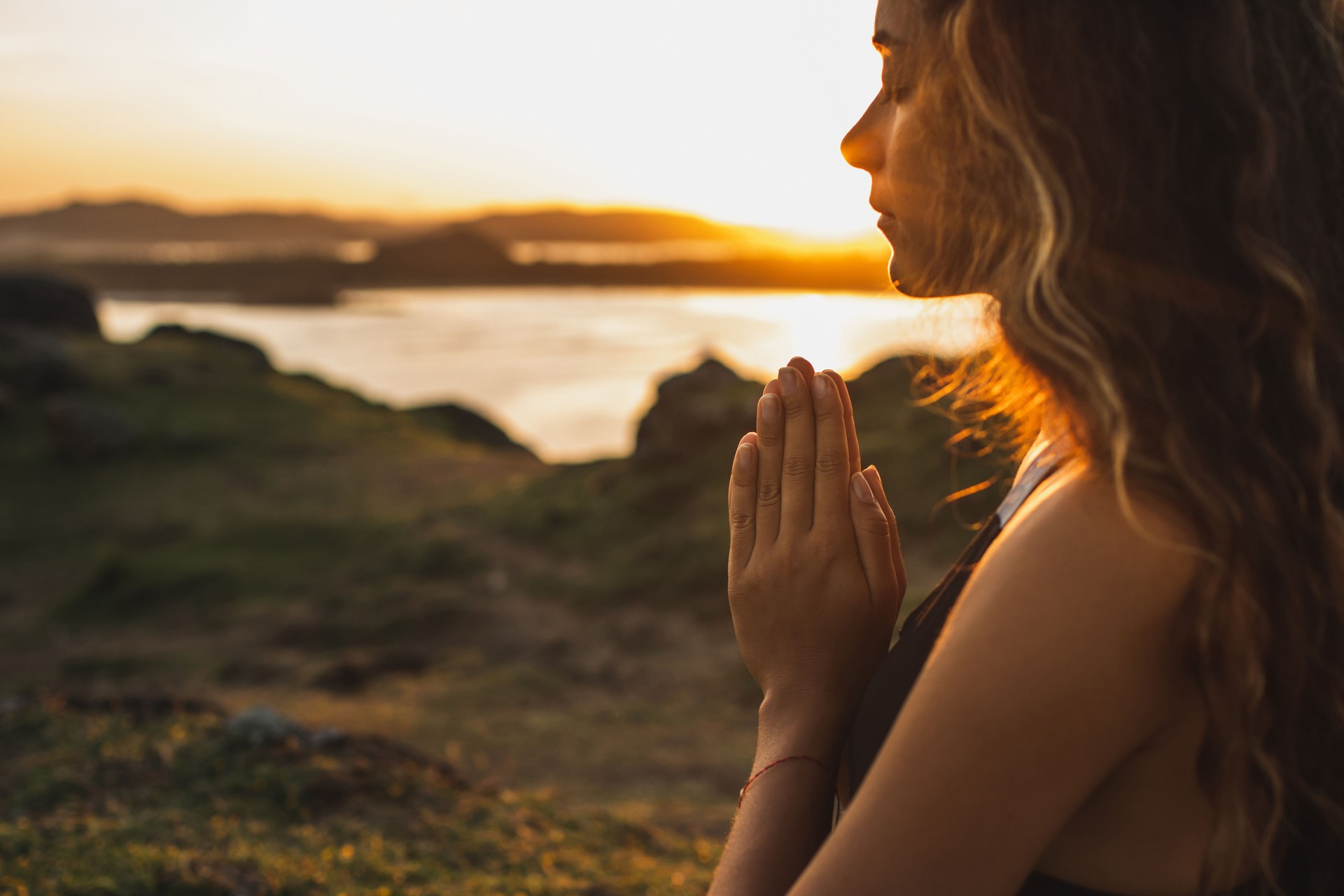 Woman praying alone at sunrise. Nature background. Spiritual and emotional concept. Sensitivity to nature